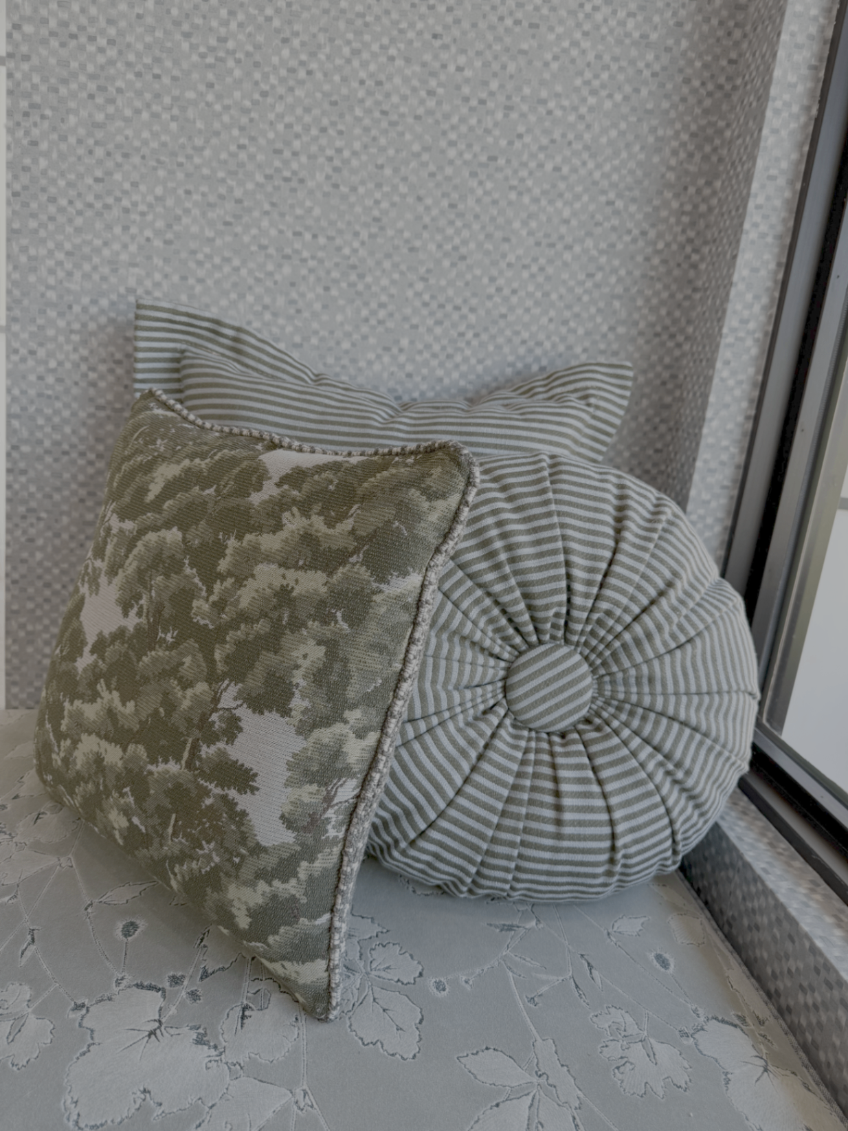 Layered pillows in olive botanical print and sage ticking stripe on a window seat