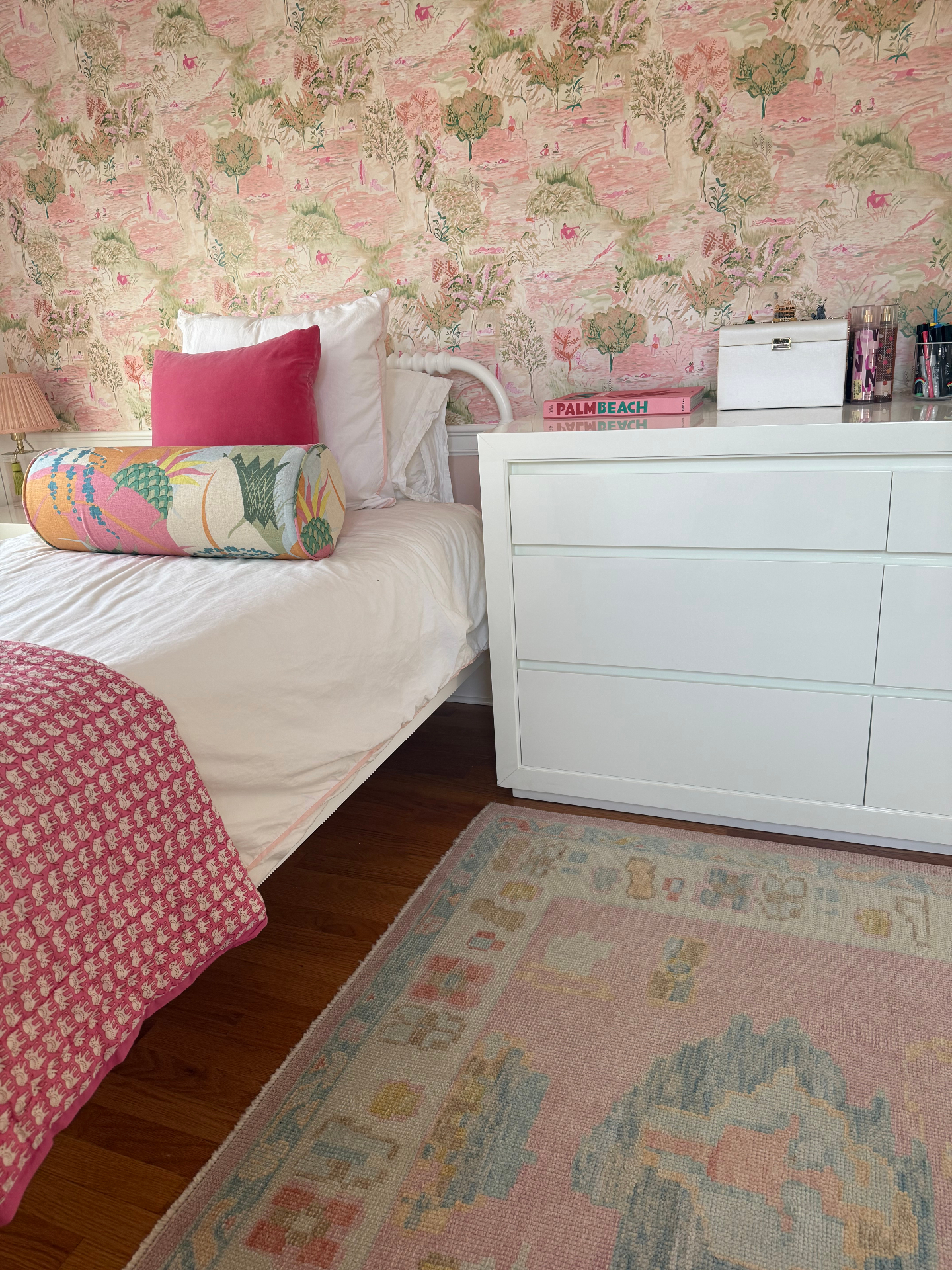 Girl's bedroom with pink pastoral toile wallpaper, white dresser, and hot pink velvet pillow