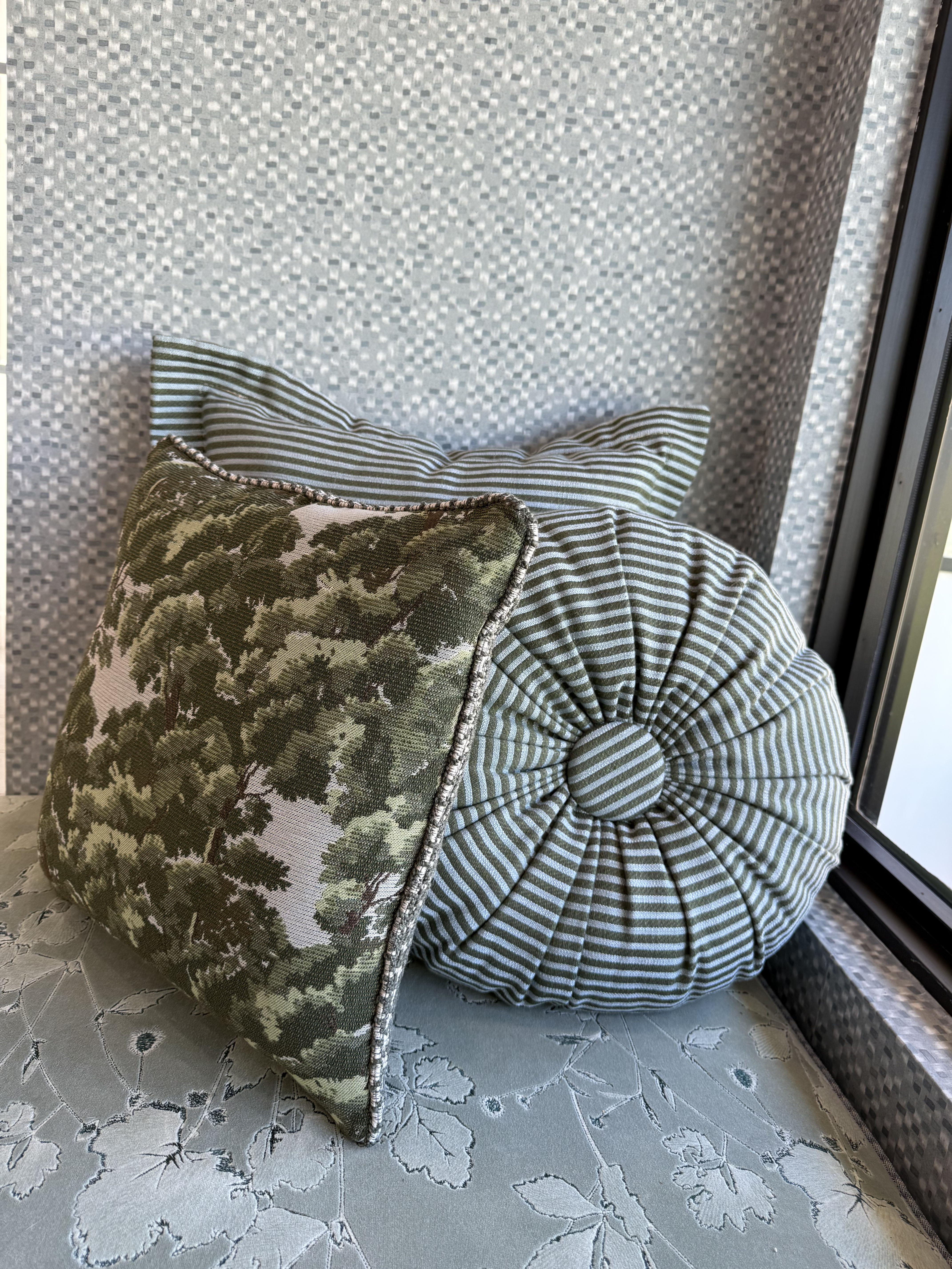 Layered pillows in olive botanical print and sage ticking stripe on a window seat