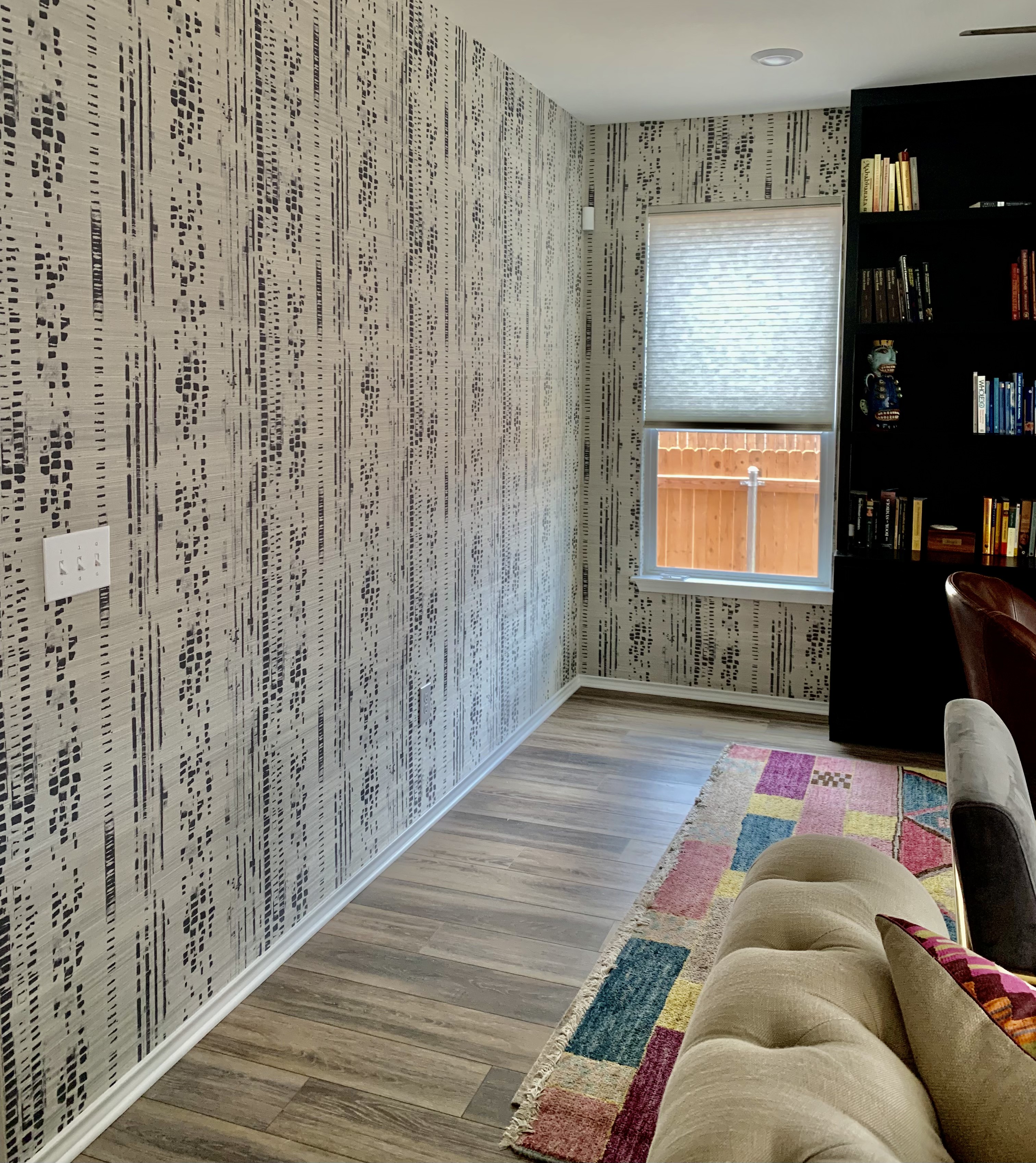 Home study with textural black and cream grasscloth wallpaper and dark built-in shelving