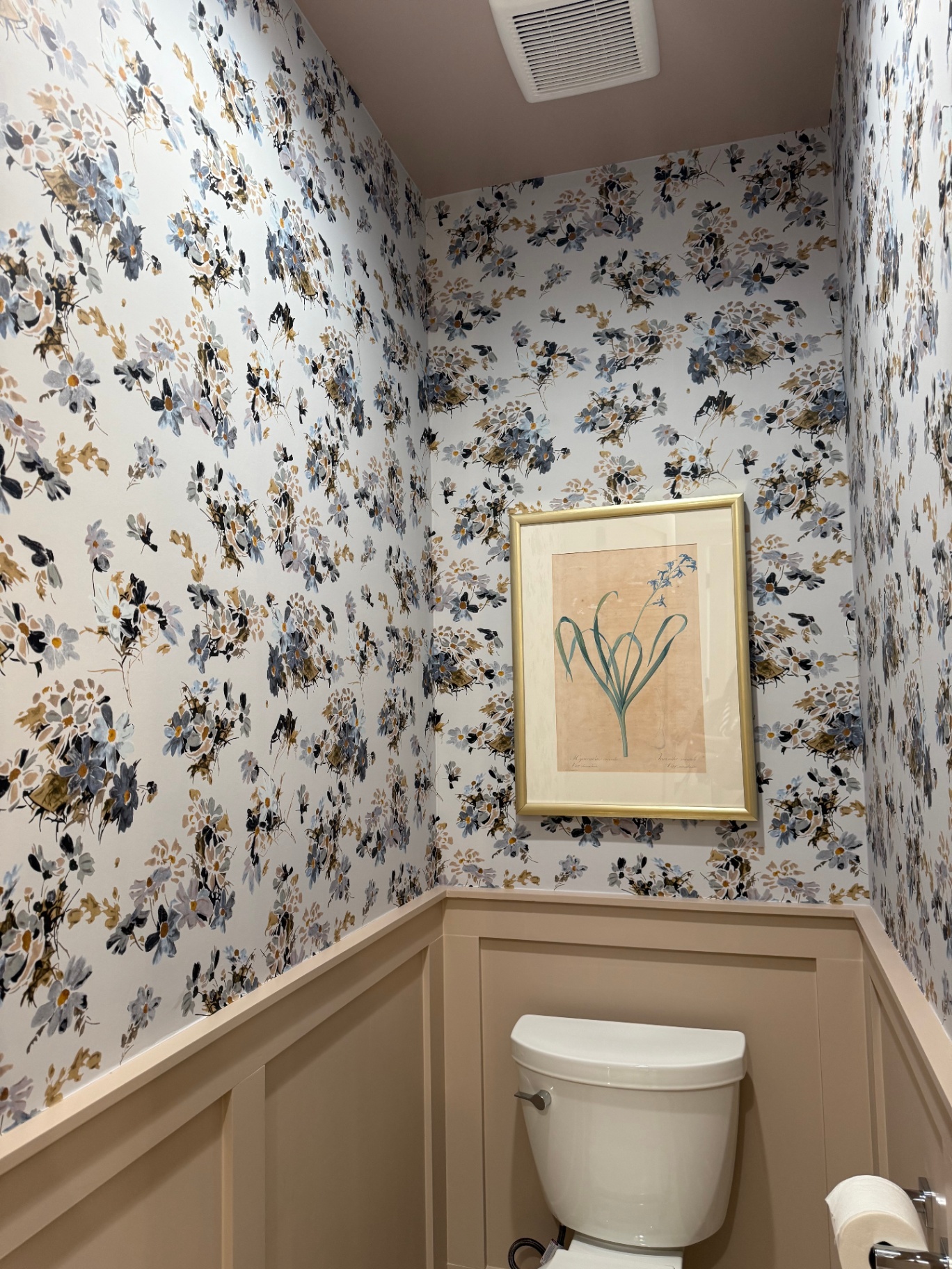 Powder room with watercolor floral wallpaper, cream wainscoting, and botanical print