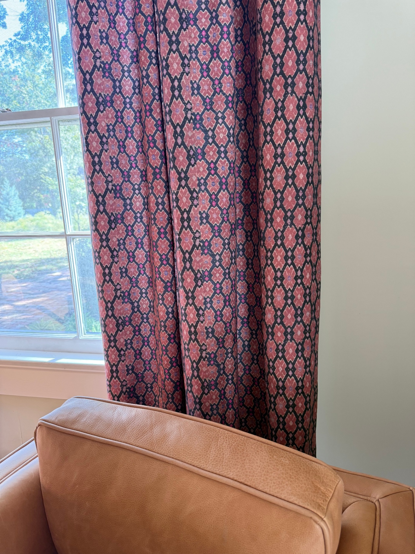 Close-up of rose and navy diamond-pattern drapery beside a sunlit window